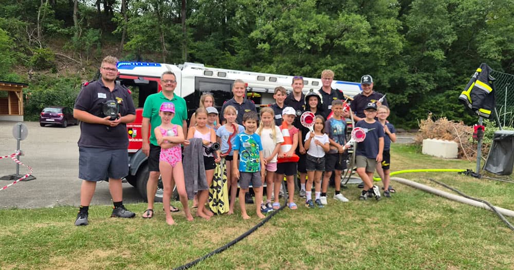 Jugendfeuerwehr mit Kindern und Betreuern vor einem Feuerwehrauto in Österreich