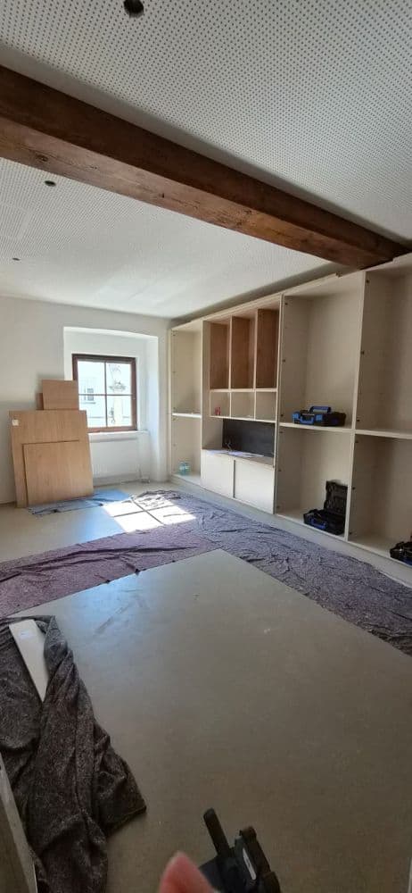 Einbauküche im Rohbau mit Holzbalken und Fenster in einem Raum